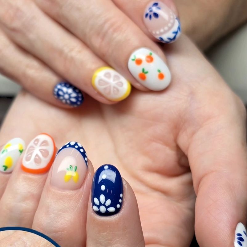Hand-painted gel nail art with citrus and blue floral designs